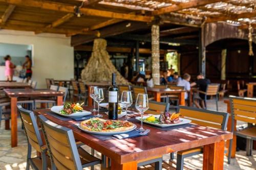 una mesa de madera con dos platos de comida y copas de vino en Lavanda Mobile Home at Terra Park Spiritos camp, en Kolan