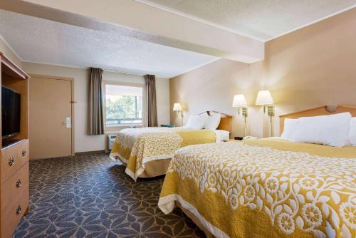 a hotel room with two beds and a television at Days Inn by Wyndham Fairmont in Fairmont