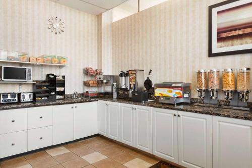 a kitchen with white cabinets and a counter top at Travelodge by Wyndham North Battleford in North Battleford