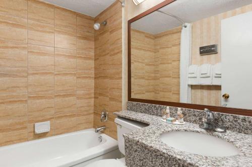 a bathroom with a tub and a sink and a toilet at Travelodge by Wyndham North Battleford in North Battleford