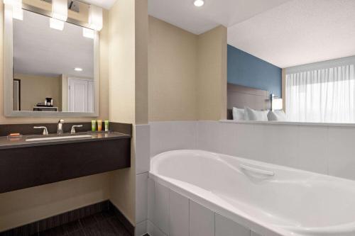 a bathroom with a tub and a sink and a mirror at Wyndham Garden Niagara Falls Fallsview in Niagara Falls