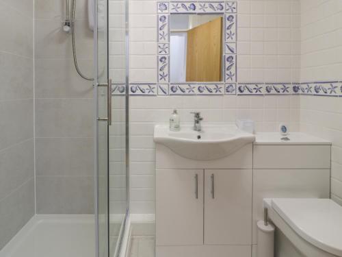 a white bathroom with a sink and a shower at 25 South Snowdon Wharf in Porthmadog