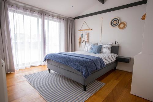 een slaapkamer met een bed met een gestreept tapijt en ramen bij Unieke woonboot in Harlingen in Harlingen