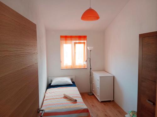 Surf & joy - Croatia vacation rentals seaview apartment في أوكروغ غورنيي: غرفة نوم صغيرة بها سرير ونافذة