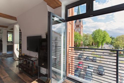 a room with a balcony with a large window at Apartamenty Strażacka - Loft Brooklyn in Szczecinek