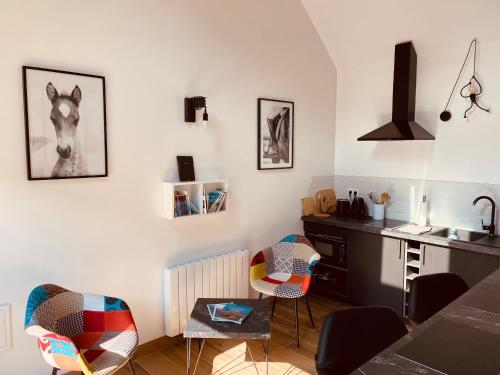 - une cuisine avec un bureau et des chaises dans la chambre dans l'établissement Gîtes L'Ancienne Ecurie - L'Ancien Atelier, à Saint-Quentin-en-Tourmont