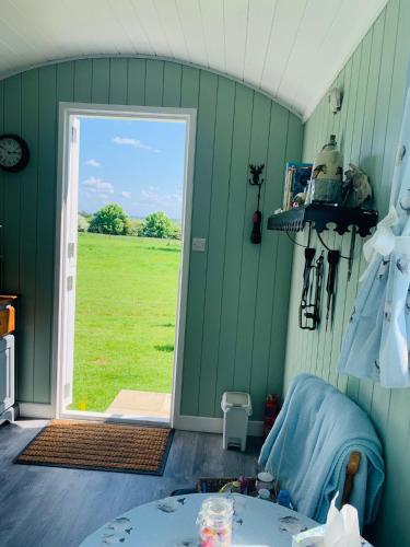 a room with a door leading to a yard with a field at Bells Meadow Shepherds Hut in Kings Lynn