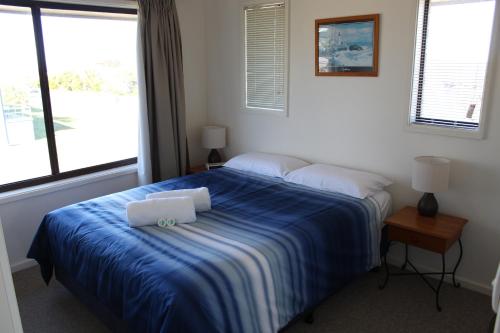 a bedroom with a blue bed with two pillows on it at Narooma Palms Holiday Apartments in Narooma