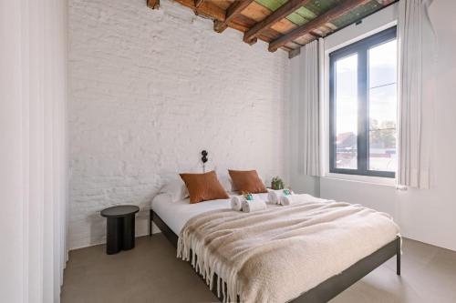 a white bedroom with a large bed and a window at House K in Kortrijk
