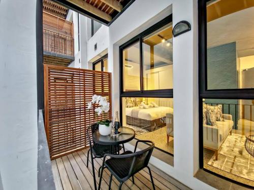 a room with a table and chairs on a balcony at Upmarket and Stylish Apartment With Rooftop Pool. in Cape Town