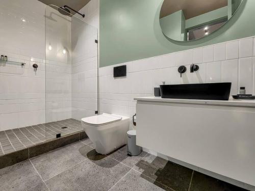 a bathroom with a toilet and a sink and a mirror at Upmarket and Stylish Apartment With Rooftop Pool. in Cape Town