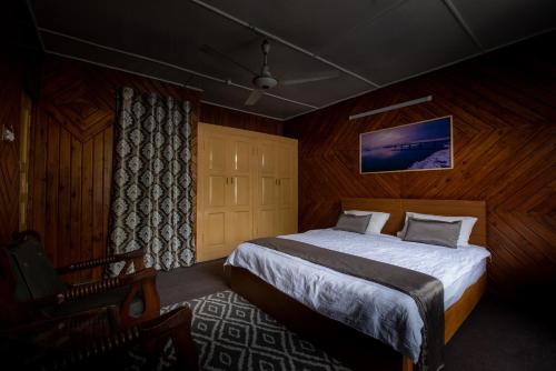 ein Schlafzimmer mit einem Bett und einem Stuhl darin in der Unterkunft Sultan's Guest House in Skardu