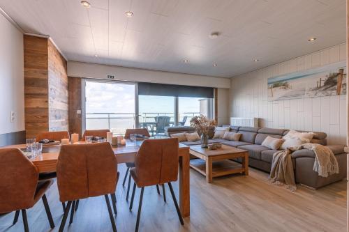 a living room with a table and a couch at Magnificent Apartment with Great Panoramic Seaview in De Haan