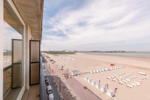 a view of a beach with umbrellas and a building at Stunning Seaview apt on 7th floor at beachfront in Knokke-Heist