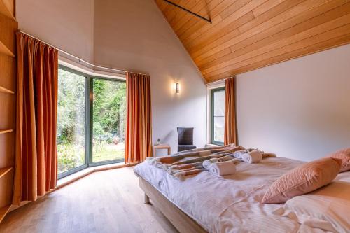 1 dormitorio con cama grande y ventana grande en Peacefully located villa with stunning garden and hot tub, en Oostkamp