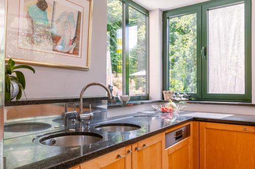 una cocina con 2 lavabos y 2 ventanas en Peacefully located villa with stunning garden and hot tub, en Oostkamp