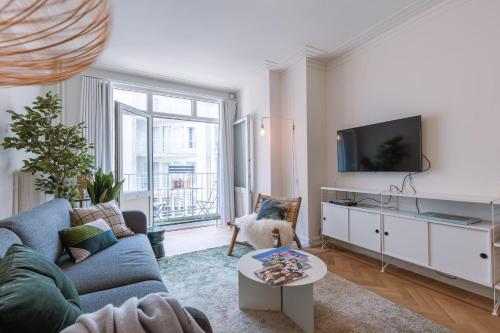 un salon avec un canapé bleu et une télévision dans l'établissement Warm & cozy lateral seaview apartment, à Ostende