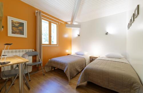 Habitación con 2 camas, escritorio y mesa. en Gîte du petit Val du Gers en Savignac-Mona