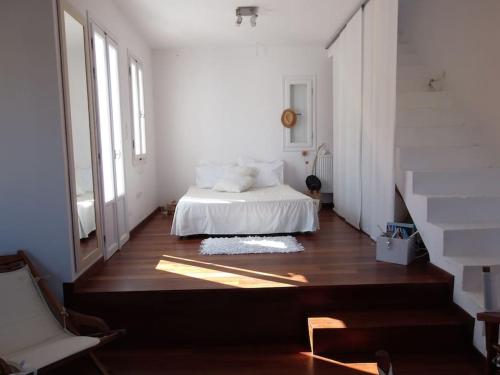 Cette chambre comprend un lit avec des draps blancs et du parquet. dans l'établissement Ageri Home, à Karavostasi