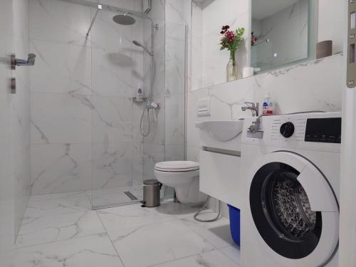 een witte badkamer met een toilet en een douche bij Mihaly Apartment in Sarandë
