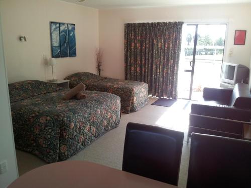 a hotel room with a bed and a couch at Norfolk Motel & Campervan Park in Awanui