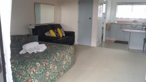 Habitación de hotel con cama y silla en Norfolk Motel & Campervan Park, en Awanui