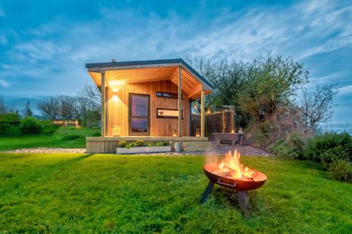 a tiny house with a barbecue in the yard at Luxury Glamping Cabin with Outdoor Bath on Cornish Flower Farm in Truro