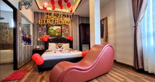 a bedroom with a bed and a chair with a happy birthday sign at Milan Corner Hotel in Vung Tau