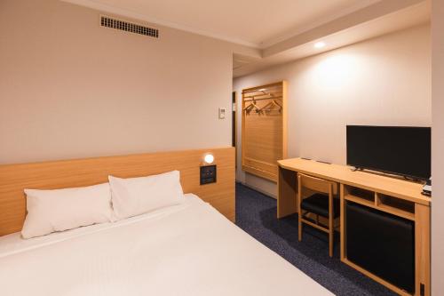 Habitación de hotel con cama y escritorio con TV. en Sotetsu Fresa Inn Tokyo-Akasaka, en Tokio