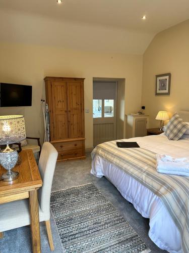 a bedroom with a bed and a table and a television at Canaston Oaks in Narberth