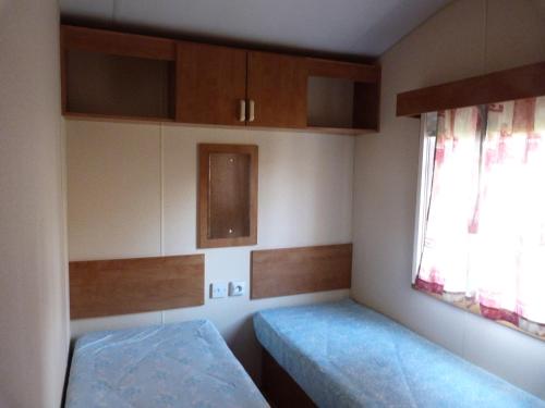 a small room with two beds and a window at camping la rivière in Vabre-Tizac