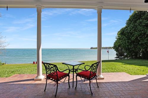 a table and two chairs sitting under a porch with the ocean at Somerset - A Private Retreat in Niagara on the Lake