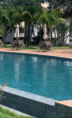einen Pool mit Stühlen und Sonnenschirmen in einem Resort in der Unterkunft Apartamento Vila do Lago in Mata de Sao Joao