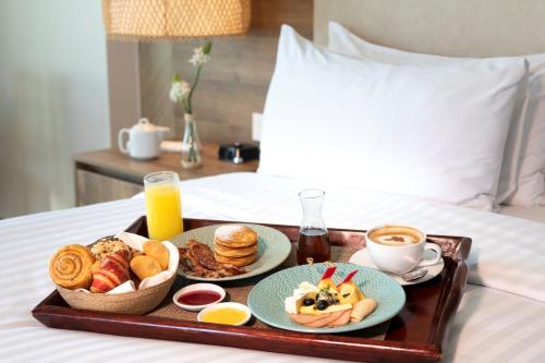 a tray of breakfast foods and coffee on a bed at Santa Marta Marriott Resort Playa Dormida in Santa Marta