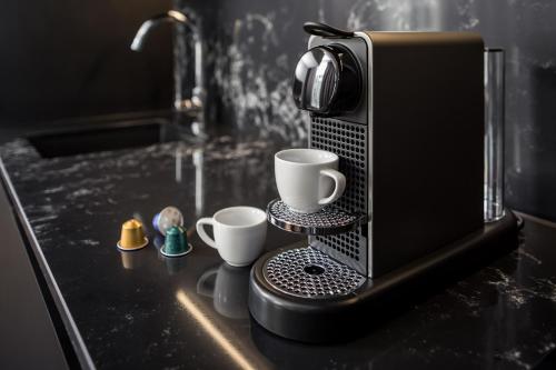 a counter with two cups and a coffee maker at AMANO Home Leipzig in Leipzig