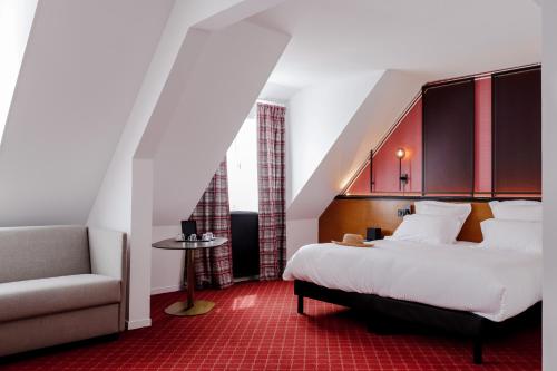a hotel room with a bed and a chair at Hôtel Les Jardins de Deauville in Saint-Martin-aux-Chartrains