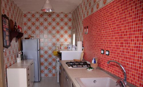 a red tiled kitchen with a sink and a stove at SAN FRANCESCO 67 - Erice Vetta in Erice