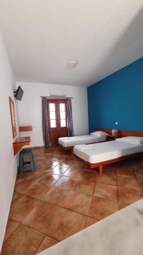 Cette chambre comprend 2 lits et un mur bleu. dans l'établissement Blue Sand, à Kalymnos