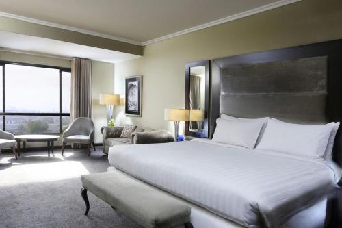 a bedroom with a large bed and a living room at Four Points by Sheraton Lahore in Lahore