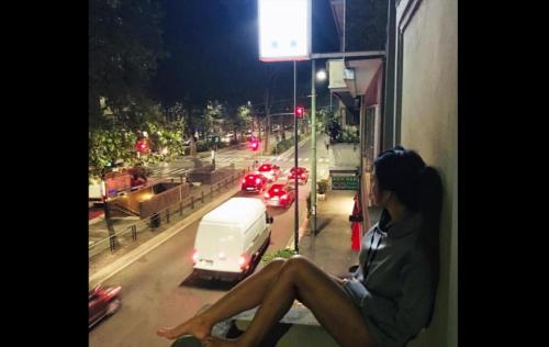 a woman sitting on a window sill looking out at a street at Hotel MM Dateo in Milan