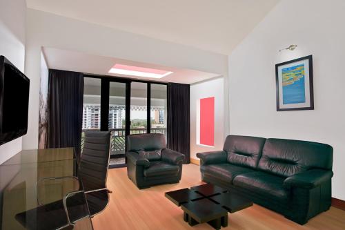 a living room with a leather couch and chairs at Le Meridien Kochi in Cochin