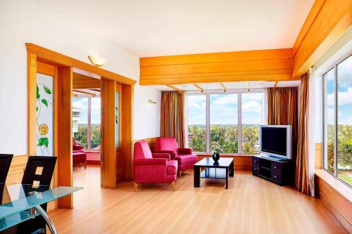a living room with pink chairs and a television at Le Meridien Kochi in Cochin