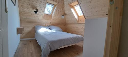 a small bedroom with a bed in a wooden wall at Orfűi Gomba Vendégház in Orfű