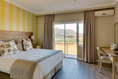 a bedroom with a bed and a desk and a window at Protea Hotel by Marriott Stellenbosch & Conference Centre in Stellenbosch
