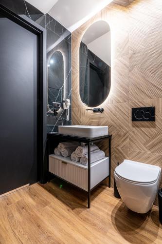 a bathroom with a sink and a toilet and a mirror at Góralski Resort Pool & SPA in Białka Tatrzańska