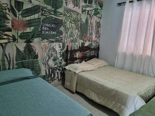 Casa Faisão في نوفا ليما: سريرين في غرفة ذات جدار بالنباتات