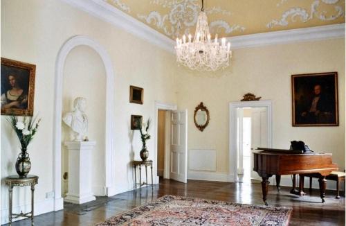 a living room with a piano and a chandelier at Newcourt Manor in Hereford