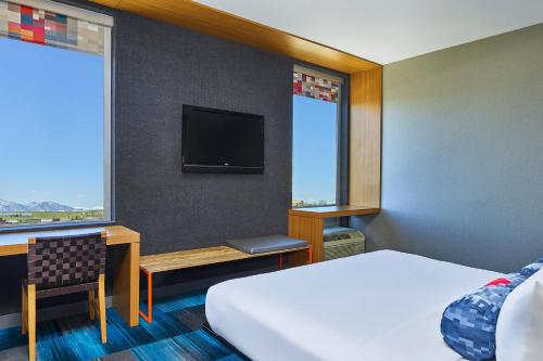 a hotel room with a bed and a desk and a tv at Aloft Broomfield Denver in Broomfield
