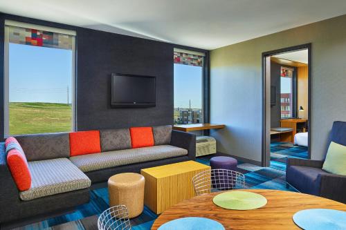 a living room with a couch and a tv at Aloft Broomfield Denver in Broomfield