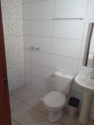 a white bathroom with a toilet and a sink at Pousada Nascer da Lua in São Thomé das Letras